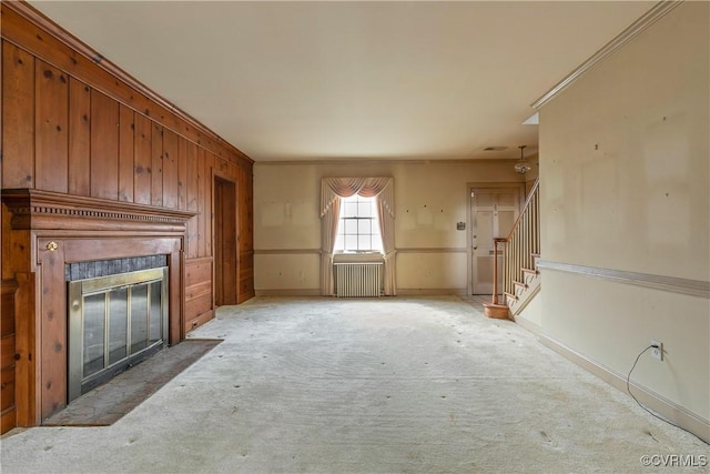 unfurnished living room featuring stairway, radiator, baseboards, a fireplace with flush hearth, and light carpet