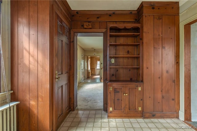 hall with light floors, wood walls, and light carpet