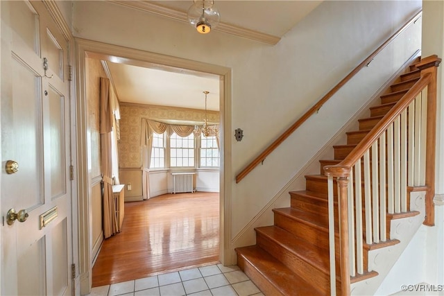 foyer entrance with light tile patterned floors, stairway, radiator, and ornamental molding