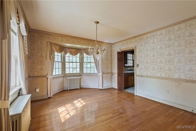 unfurnished dining area featuring wallpapered walls, hardwood / wood-style flooring, radiator heating unit, and wainscoting