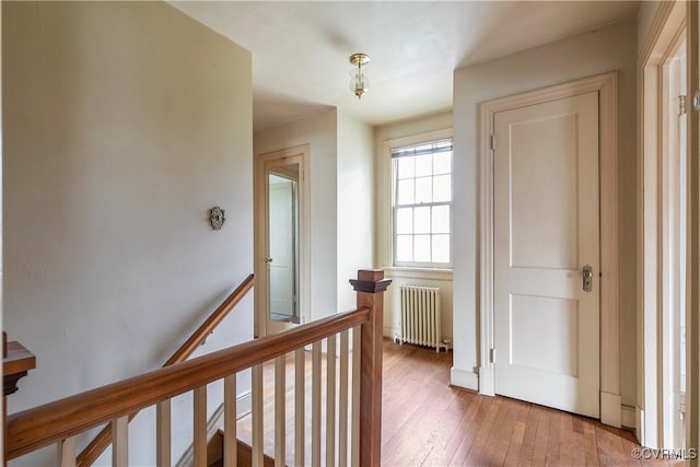 hallway featuring an upstairs landing, radiator heating unit, and hardwood / wood-style flooring