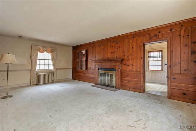 unfurnished living room with a wealth of natural light, a fireplace with flush hearth, radiator heating unit, and carpet floors