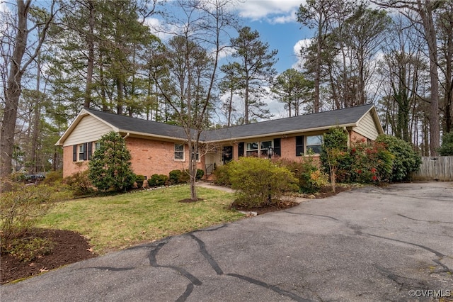 ranch-style home with brick siding, a front lawn, and fence