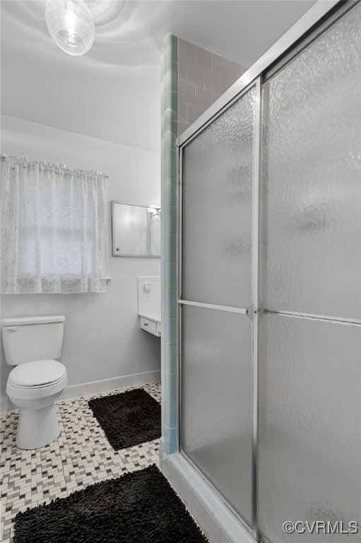 bathroom featuring a shower stall, toilet, and baseboards