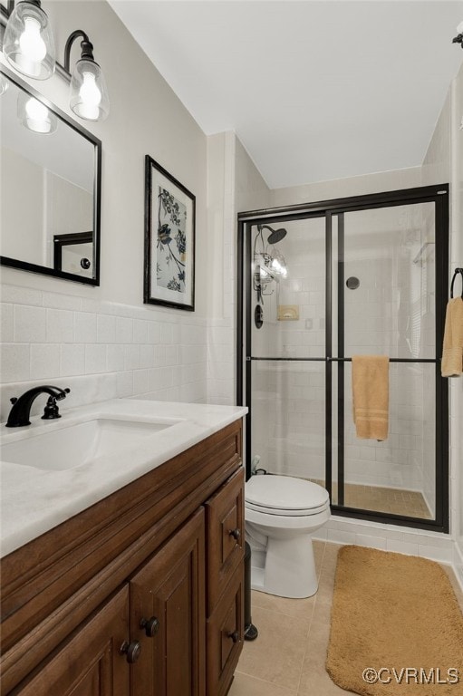 bathroom with vanity, a shower stall, tile walls, toilet, and tile patterned floors