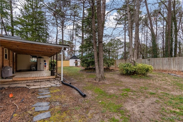 view of yard with a deck, an outbuilding, and fence