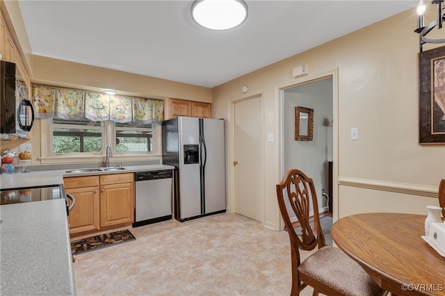 kitchen with light floors, appliances with stainless steel finishes, light countertops, and a sink