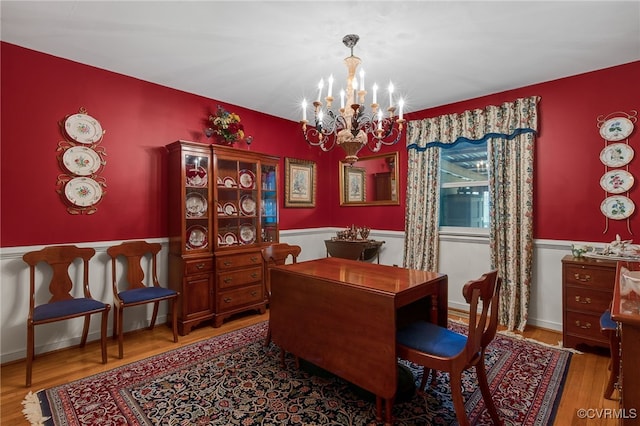 dining space featuring a chandelier, baseboards, and wood finished floors