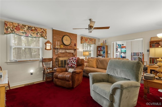 living area with visible vents, a fireplace, crown molding, and a ceiling fan