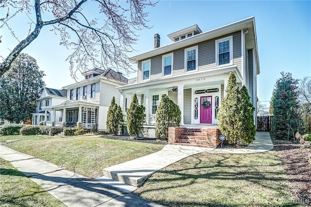 american foursquare style home with covered porch and a front lawn