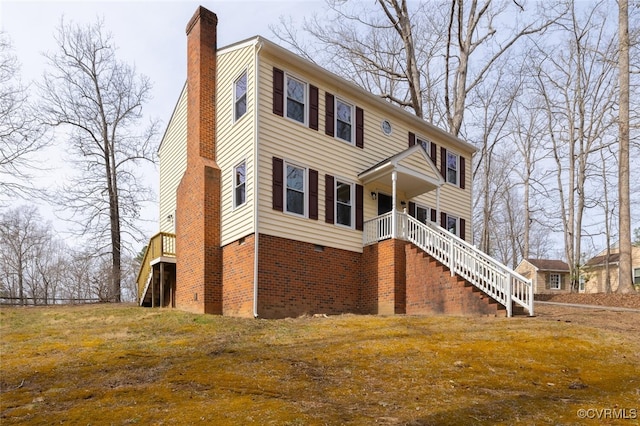 view of front of house featuring brick siding, stairway, and a chimney