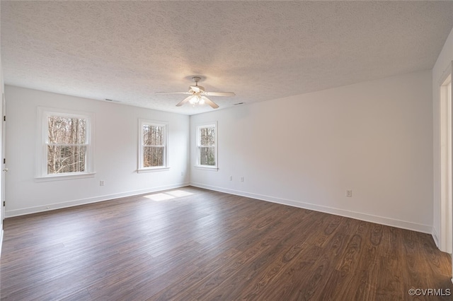 spare room with a textured ceiling, dark wood-style floors, baseboards, and ceiling fan