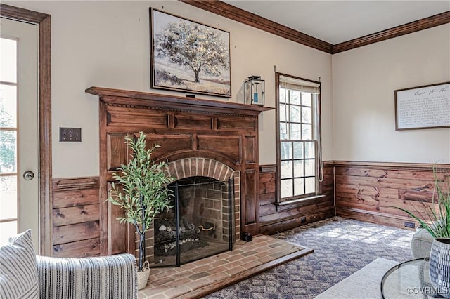 living room featuring a wainscoted wall, a brick fireplace, crown molding, and wooden walls