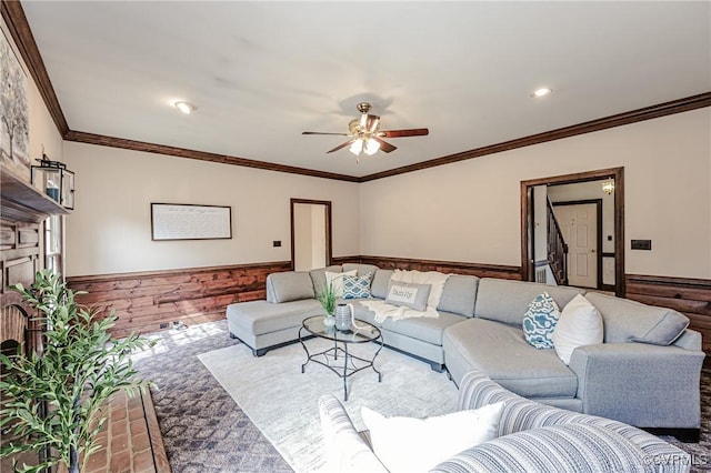 living area featuring a wainscoted wall, recessed lighting, a fireplace, ceiling fan, and ornamental molding