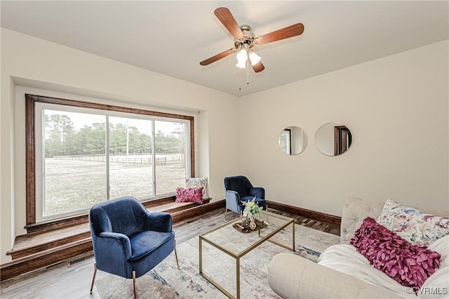 living room featuring ceiling fan, baseboards, and wood finished floors