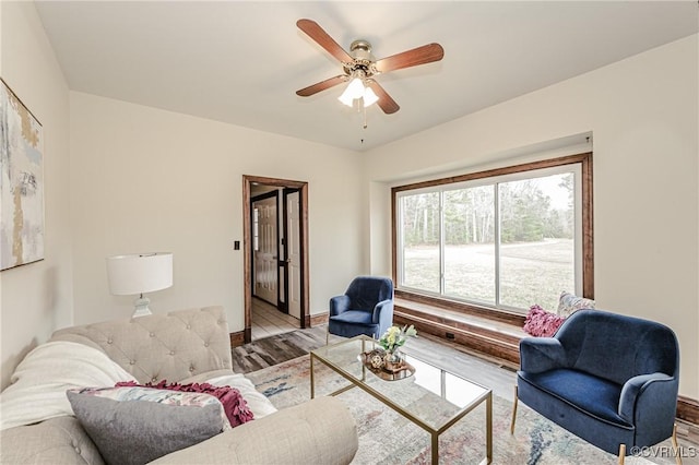 living room featuring baseboards, a ceiling fan, and wood finished floors