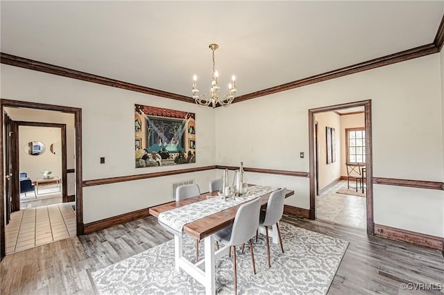 dining room with visible vents, crown molding, baseboards, and wood finished floors