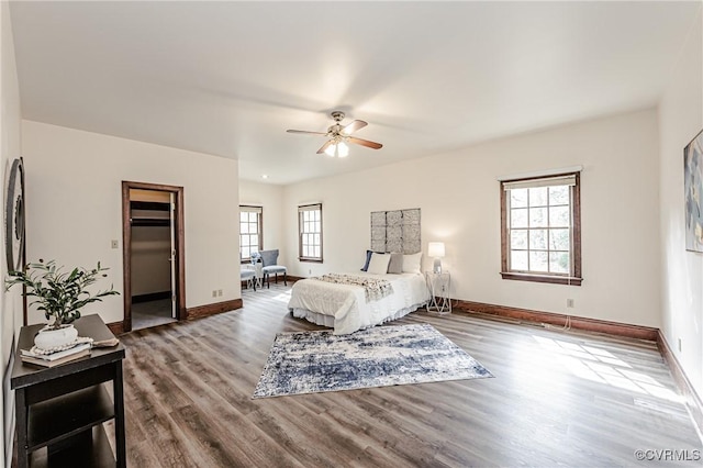 bedroom with multiple windows, ceiling fan, baseboards, and wood finished floors