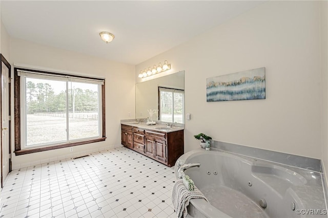 full bathroom with double vanity, plenty of natural light, a tub with jets, and a sink