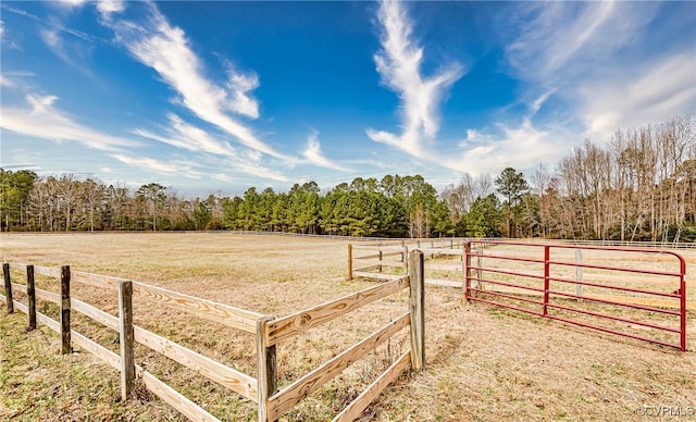 view of yard featuring a view of trees, a rural view, and fence