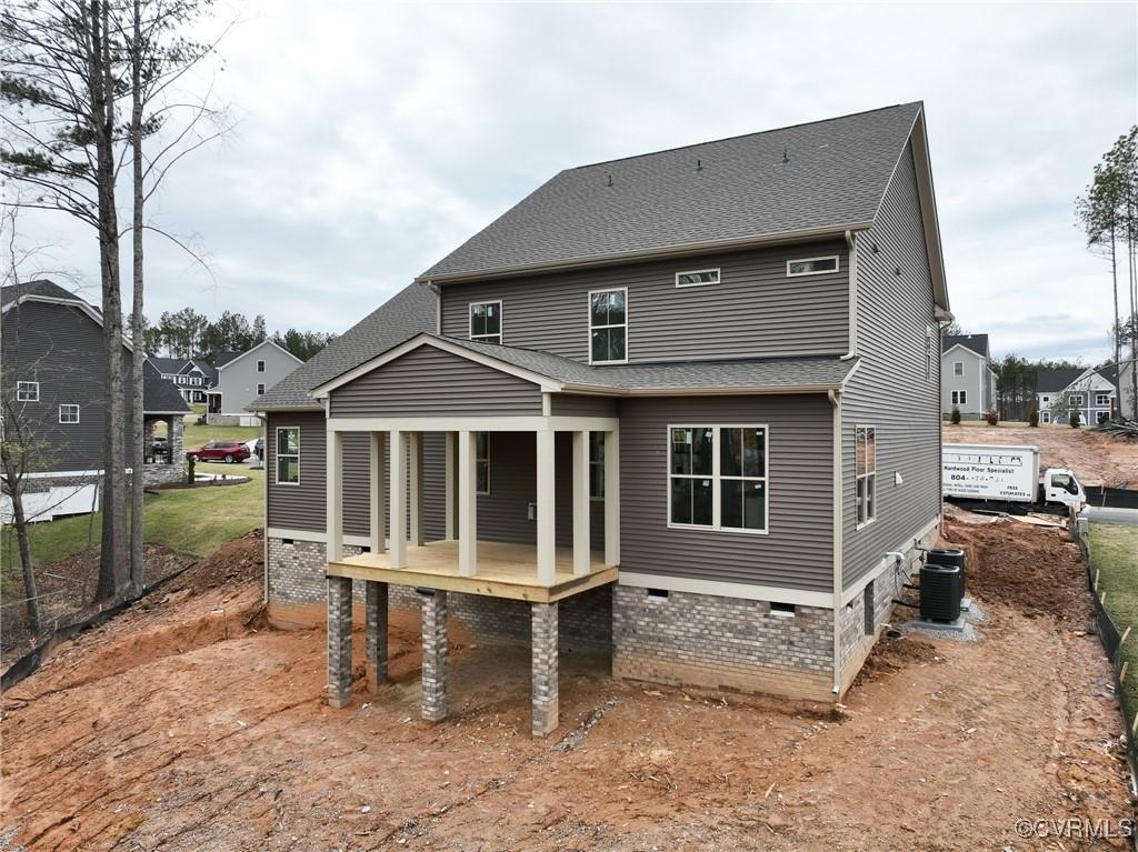 back of house featuring central air condition unit, a shingled roof, and a residential view