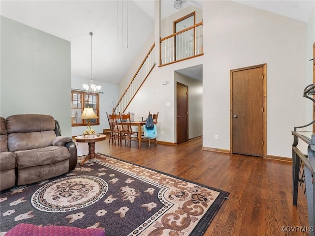 living area with wood finished floors, baseboards, high vaulted ceiling, an inviting chandelier, and stairs