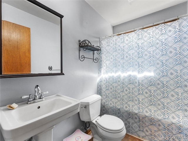 full bath featuring curtained shower, toilet, and a sink