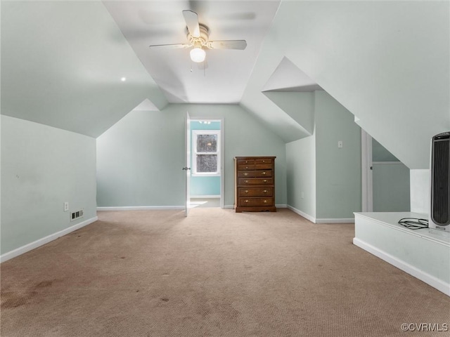 additional living space featuring visible vents, baseboards, lofted ceiling, light colored carpet, and ceiling fan