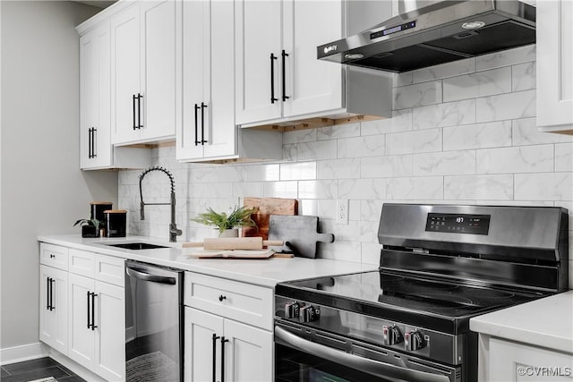 kitchen with a sink, appliances with stainless steel finishes, light countertops, and wall chimney range hood