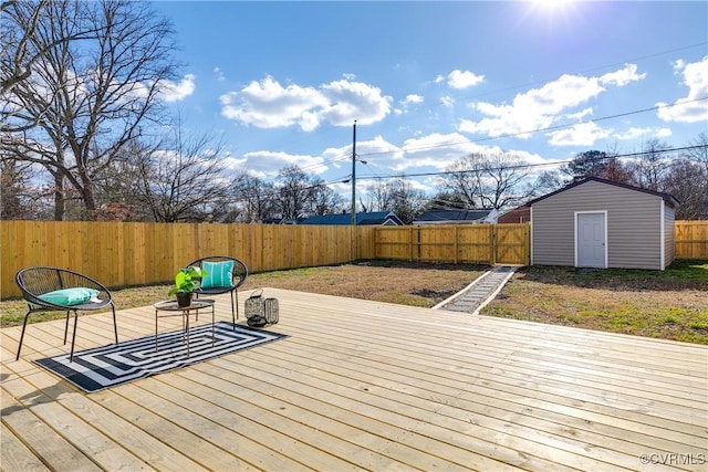 wooden terrace with a storage unit, an outdoor fire pit, an outdoor structure, and a fenced backyard