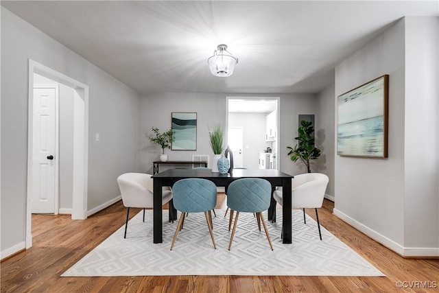 dining space featuring visible vents, a notable chandelier, wood finished floors, and baseboards