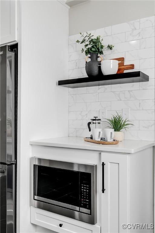 room details featuring open shelves, tasteful backsplash, stainless steel appliances, white cabinets, and light countertops