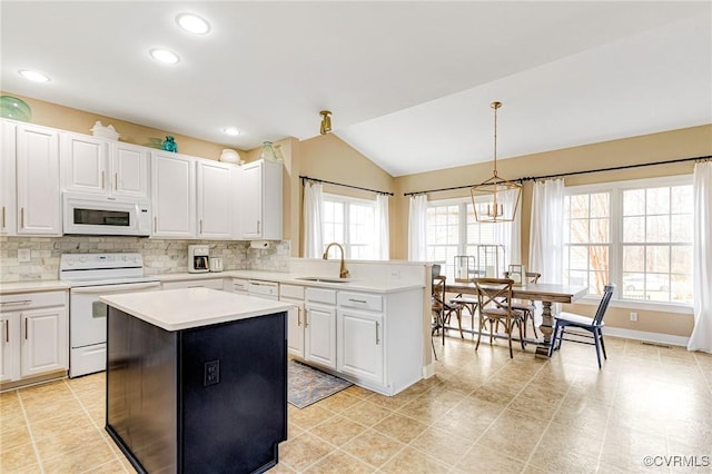 kitchen with backsplash, white appliances, light countertops, and a sink