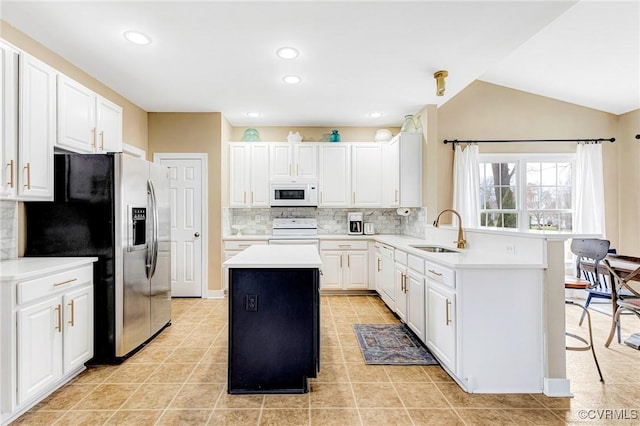 kitchen featuring white microwave, a peninsula, a sink, stainless steel refrigerator with ice dispenser, and range with electric stovetop