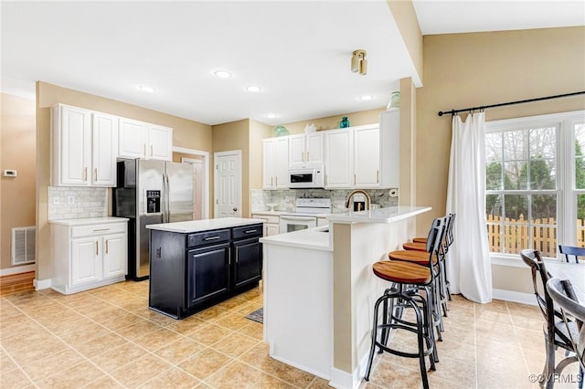 kitchen featuring visible vents, white appliances, white cabinets, and light countertops