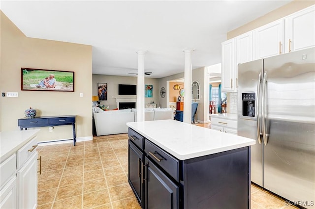 kitchen with decorative columns, stainless steel fridge, a fireplace, and white cabinetry