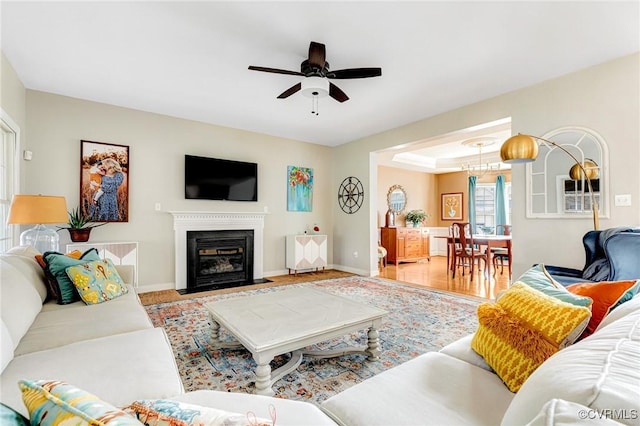 living area with a fireplace with flush hearth, baseboards, and ceiling fan