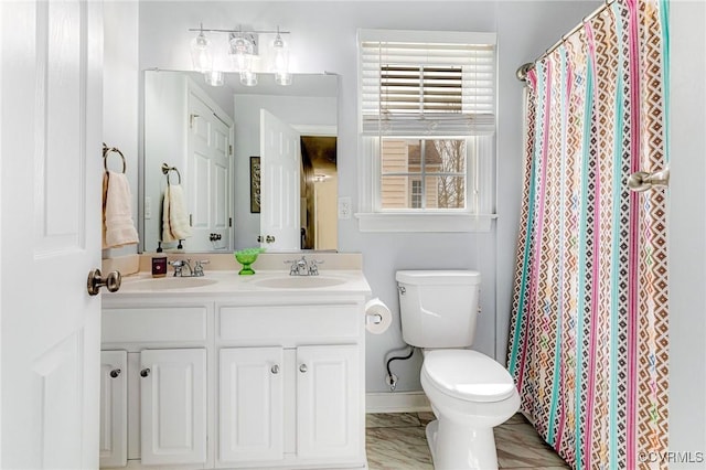 full bath featuring a sink, curtained shower, toilet, and double vanity