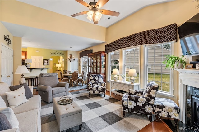 living area with wood finished floors, ceiling fan with notable chandelier, visible vents, and a high end fireplace