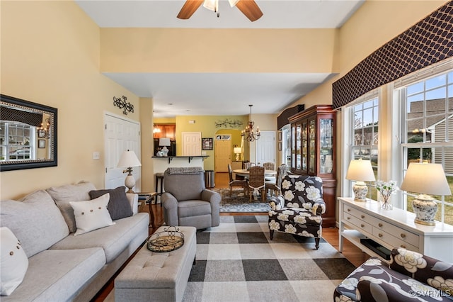 living area featuring wood finished floors and ceiling fan with notable chandelier