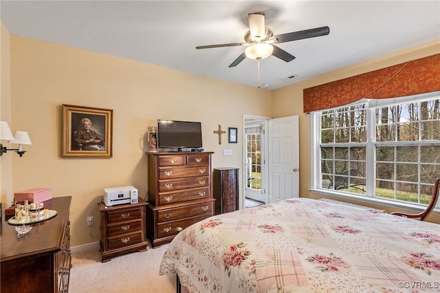 bedroom featuring visible vents, light colored carpet, baseboards, and ceiling fan