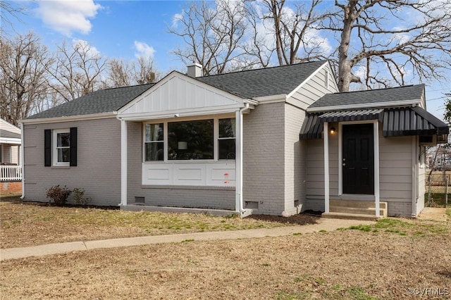 view of front of house featuring a chimney, brick siding, roof with shingles, and crawl space