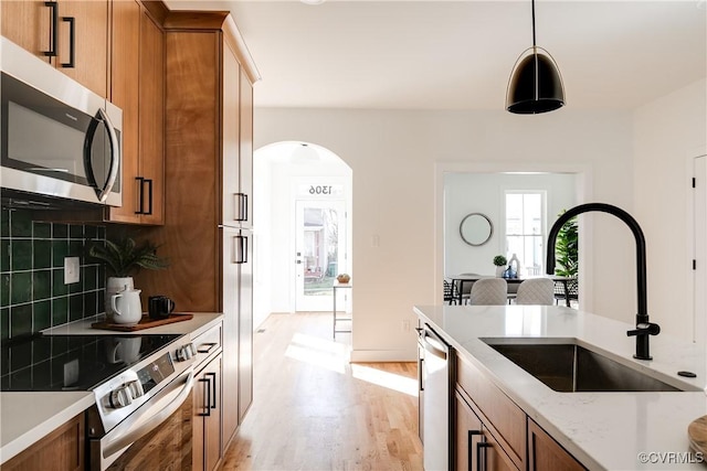 kitchen featuring brown cabinetry, stainless steel appliances, tasteful backsplash, and a sink