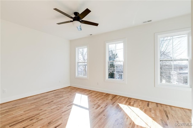 spare room with a wealth of natural light, visible vents, baseboards, and wood finished floors