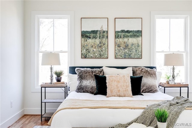 bedroom with multiple windows, baseboards, and wood finished floors