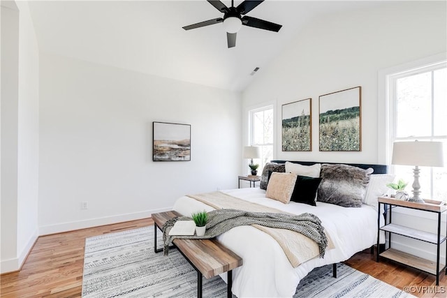 bedroom with baseboards, high vaulted ceiling, wood finished floors, and a ceiling fan