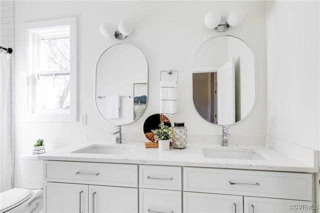 full bathroom with double vanity, toilet, and a sink