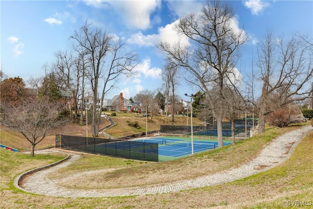 view of basketball court with a tennis court and fence