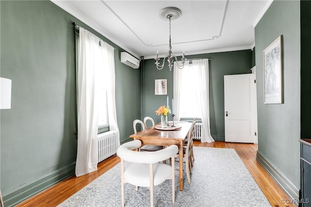 dining space featuring radiator, baseboards, a wall unit AC, ornamental molding, and light wood-style floors