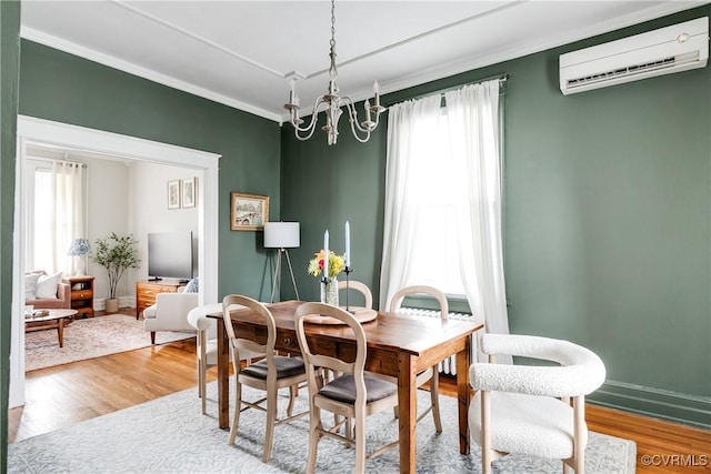 dining area with ornamental molding, wood finished floors, a wall mounted air conditioner, and a healthy amount of sunlight